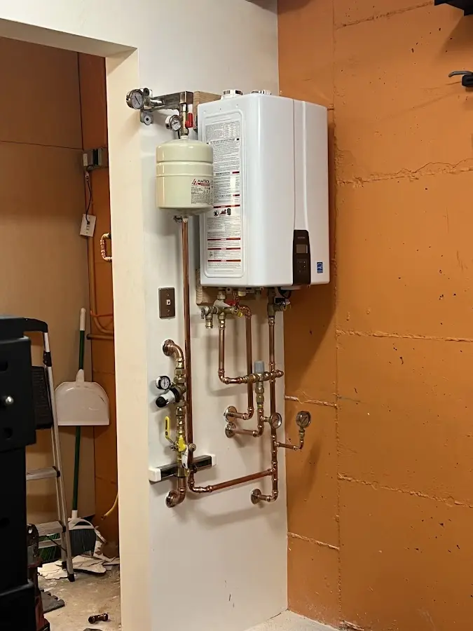 Plumbing technician inspecting water heater connections in Harrietstown
